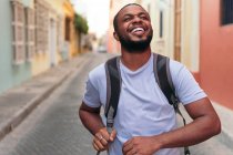 Young African American man carrying backpack while standing outdoors — Stock Photo