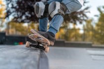 Crop adolescent saut avec skateboard et montrant cascade sur la rampe dans skate park — Photo de stock