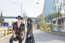 Grave coppia elegante in abiti hipster in piedi guardando la fotocamera lungo la strada in estate — Foto stock