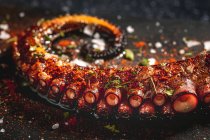 Delizioso tentacolo di polpo grigliato servito con spezie su tavola di legno — Foto stock