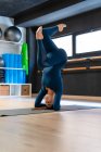 Full body of fit female in sportswear doing supported headstand variation pose while practicing yoga in fitness studio — Stock Photo