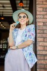 Lächelnde junge Frau in stylischer Kleidung mit Handy in Cafeteria mit Lampen — Stockfoto