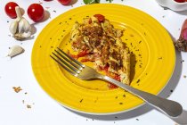 Délicieuse omelette au persil haché sur assiette contre tomates séchées au soleil sur fond blanc — Photo de stock