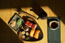 Du dessus de l'assiette avec des rouleaux de sushi assortis servis sur la table avec des baguettes et de la sauce soja au restaurant japonais — Photo de stock