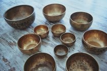 Assorted round shaped singing bowls with spots on metal surface on rough floor on blurred background — Stock Photo