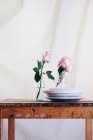 Rose rosa all'interno di vasi di vetro disposti su tavolo di legno sullo sfondo neutro — Foto stock