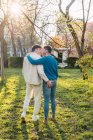 Вернуться к просмотру любящих ЛГБТ пара мужчин, обнимающих и целующихся в парке в солнечный день — стоковое фото