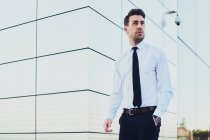 Uomo imprenditore in abbigliamento formale con orologio da polso guardando altrove in città — Foto stock