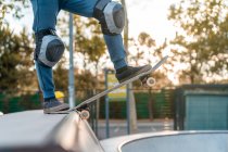 Crop teen skater standing on skateboard and preparing for showing trick on ramp in skate park — Stock Photo