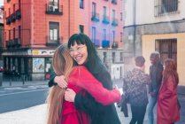 Delighted multiracial female friends hugging while standing on city street and enjoying weekend — Stock Photo