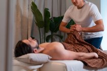 Side view of anonymous crop masseur doing Thai massage for male customer in modern spa salon — Stock Photo