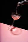 Анонимный человек, наливающий розовое игристое вино в элегантный бокал купе на двух цветном фоне — стоковое фото