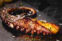 Delizioso tentacolo di polpo grigliato servito con spezie su tavola di legno — Foto stock