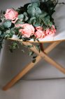 Сверху букет розовых роз с зелеными листьями лежащими на столе — стоковое фото