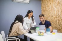 Gruppe multiethnischer Content-Mitarbeiter trifft sich am Tisch und nutzt Geräte während der Arbeit an einem Startup-Projekt — Stockfoto