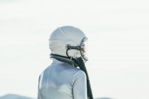 Voltar ver o homem em traje espacial e capacete olhando para longe, enquanto em pé no caminho no dia ensolarado na natureza — Fotografia de Stock