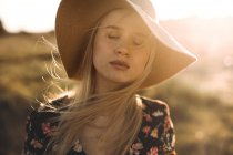 Retrato de uma bela jovem com chapéu no campo com olhos fechados — Fotografia de Stock