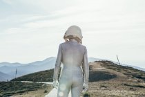 Voltar ver o homem em traje espacial e capacete olhando para longe, enquanto em pé no caminho no dia ensolarado na natureza — Fotografia de Stock