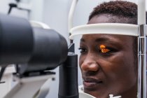 Optométriste ajustant le rétinographe lors de l'étude de la vue d'une femme noire — Photo de stock