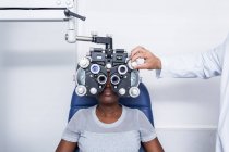 Оптометрист налаштування обладнання оптометрії під час вивчення зору чорної жінки — стокове фото