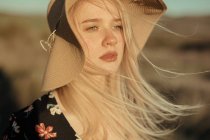 Portrait of a beautiful young woman with hat in countryside looking away — Stock Photo