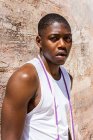 Entschlossener afroamerikanischer athletischer Rüde mit Springseil steht an einem sonnigen Tag in der Stadt an der Mauer und blickt in die Kamera — Stockfoto