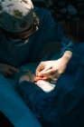 Анонимный ветеринар-хирург в латексных перчатках с хирургическими инструментами, делающий операцию на лапе животного, покрытой стерильной занавеской в ветеринарной больнице — стоковое фото