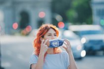 Female with red hair putting on protective medical mask in city street during coronavirus epidemic — Stock Photo