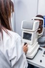 Optometrista che regola il retinografo durante lo studio della vista di una donna nera — Foto stock