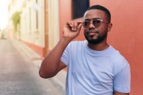African man with sunglasses walking in the city street looking at the camera. — Stock Photo