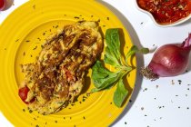 Deliziosa frittata con prezzemolo tritato su piatto contro pomodori secchi e cipolla rossa cruda su fondo bianco — Foto stock