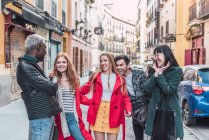 Company of happy multiracial friends in stylish clothes walking together in city street during weekend — Stock Photo