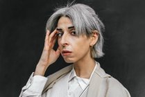 Selbstbewusste stilvolle Transgender-Frau mit grauen Haaren, die tagsüber in der Stadt den Kopf berührt — Stockfoto