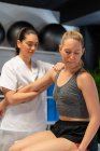 Female osteopath fitting shoulder join of patient closing eyes in pain during physiotherapy session — Stock Photo