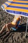 Anonimo giovane donna rossa seduta sulla sedia in spiaggia in una giornata di sole in estate — Foto stock