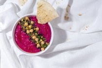 From above appetizing beetroot hummus garnished with chickpea served on fabric background with bread — Stock Photo