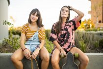 Two beautiful young women sitting resting and laughing with their long boards — Stock Photo