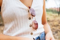 Side view of an anonymous woman with sunglasses hanging from her shirt — Stock Photo