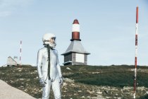 Man in spacesuit standing on rocky ground against striped rocket shaped antennas on sunny day — Stock Photo