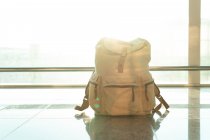 Traveling backpack placed on floor near window in departure lounge in modern airport — Stock Photo