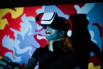 Glückliche Dame mit schwarzem T-Shirt im Raum mit bunten Lichtern und VR-Headset — Stockfoto