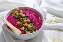 From above appetizing beetroot hummus garnished with chickpea served on fabric background with bread — Stock Photo