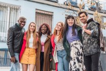 Company of happy multiracial friends in stylish clothes standing at camera together in city street during weekend — Stock Photo
