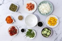 Vista dall'alto di ingredienti freschi assortiti per la tradizionale preparazione orientale del poke posizionati su un tavolo di marmo — Foto stock
