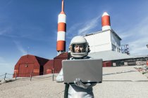Мужчина-астронавт в скафандре просматривает данные на нетбуке, стоя снаружи станции с антеннами в форме ракеты — стоковое фото