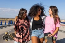 Drei schöne junge Frauen verschiedener Rassen mit ihren langen Brettern und lächelnd — Stockfoto