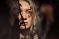 Porträt einer jungen schönen blonden Frau in einem Wald, dramatische Beleuchtung im Gesicht — Stockfoto