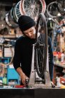 Junger männlicher Meister begutachtet Reifen am Rad während er in professioneller Reparaturwerkstatt arbeitet — Stockfoto