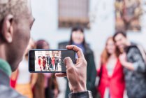 Back view of unrecognizable black male taking photo of company of multiracial friends standing on street together — Stock Photo