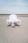 Unerkennbarer muslimischer Mann kniet auf Teppich und berührt Boden mit der Stirn, während er an sonnigen Tagen am Sandstrand betet — Stockfoto